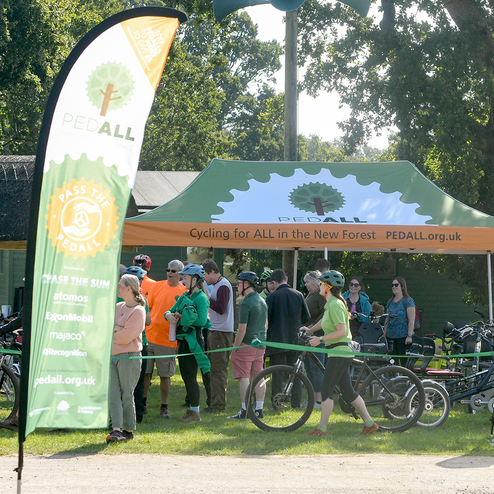 PEDALL marquee and flag with group of event attendees