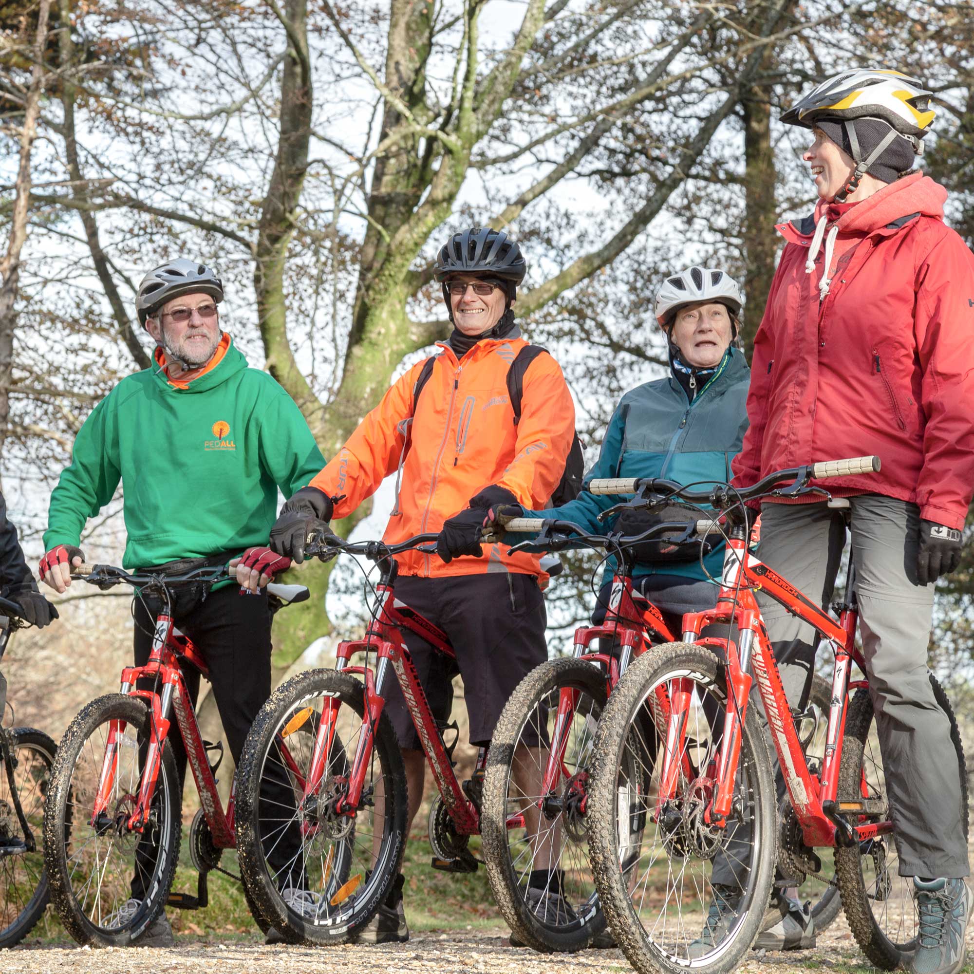 Group of mountain bikers laughing in conversation while paused on a forest hill
